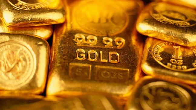 ahaufnahme mehrerer glänzender Goldbarren mit sichtbarer Prägung GOLD 999.9, 5 OZs auf einem mittig platzierten Barren.