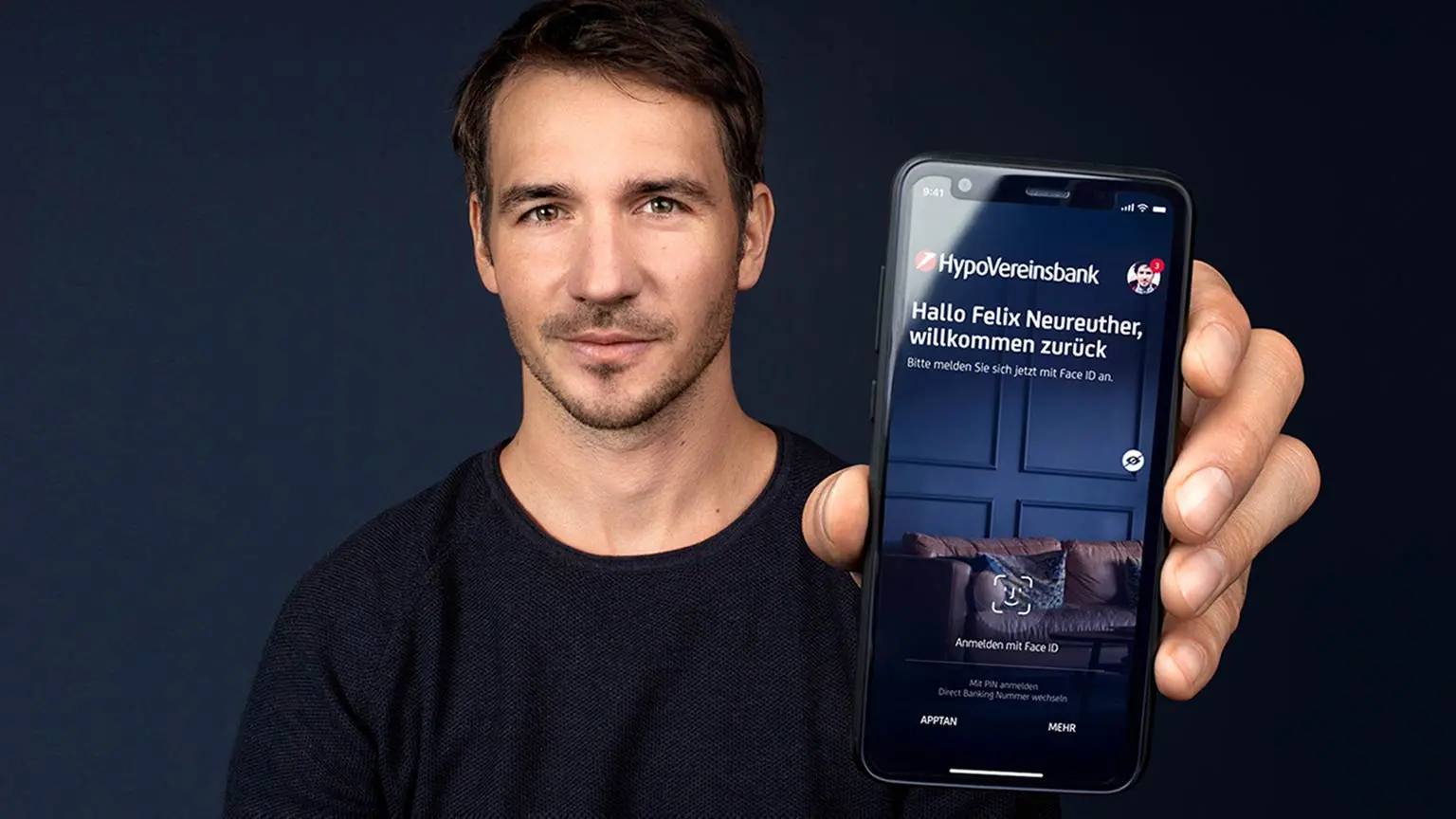Felix Neureuther hält Smartphone mit geöffneter HypoVereinsbank-App, auf der der Anmeldebildschirm mit Face-ID-Option angezeigt wird.