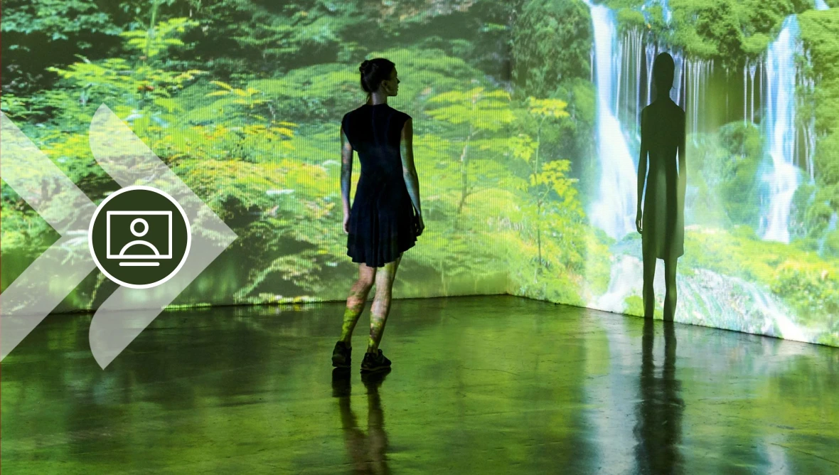 Besucher in immersiver Naturinstallation mit Wald- und Wasserfallprojektion