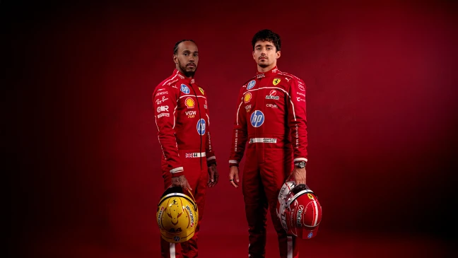 Ferrari-Fahrer in Rot: Lewis Hamilton und Charles Leclerc posieren mit Helmen und Sponsorenlogos vor einfarbig rotem Hintergrund.